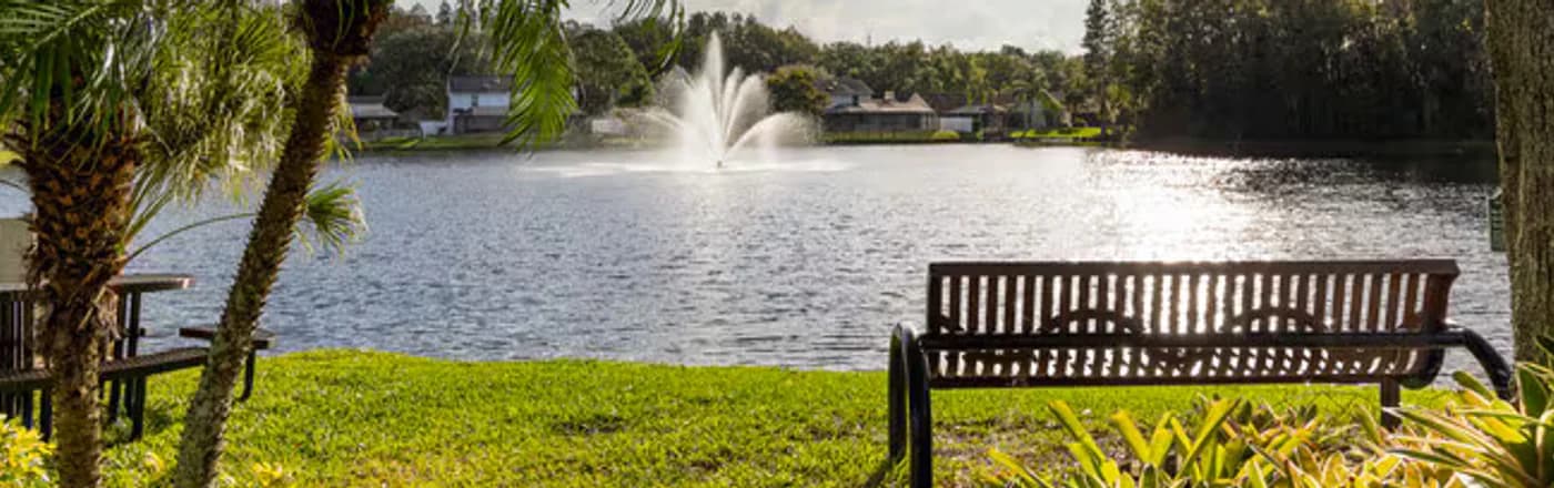 A fountain lake and park bench in a Lutz community